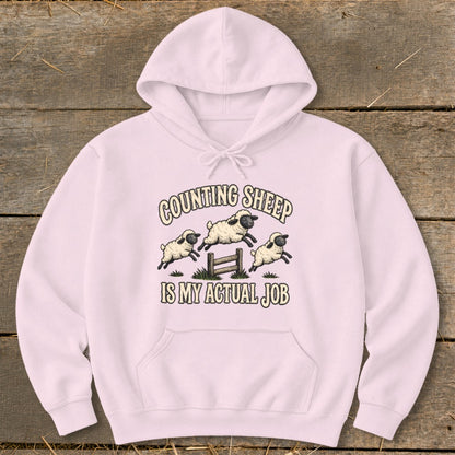 Light pink hoodie with "Counting Sheep Is My Actual Job" text and sheep graphic.