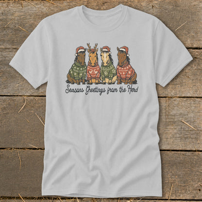 Light grey t-shirt with four horses in Christmas sweaters and Santa hats, with text "Seasons Greetings from the Herd".