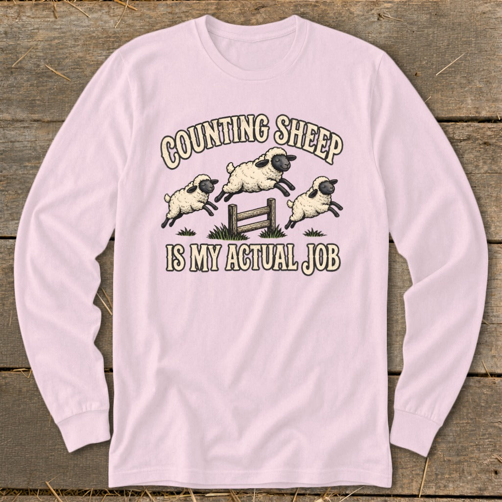 Pink long-sleeve shirt with "Counting Sheep Is My Actual Job" text and sheep graphic.