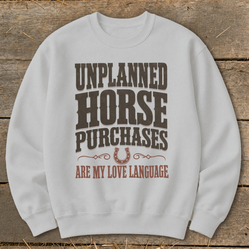 White sweatshirt with "Unplanned Horse Purchases Are My Love Language" text and horseshoe graphic.