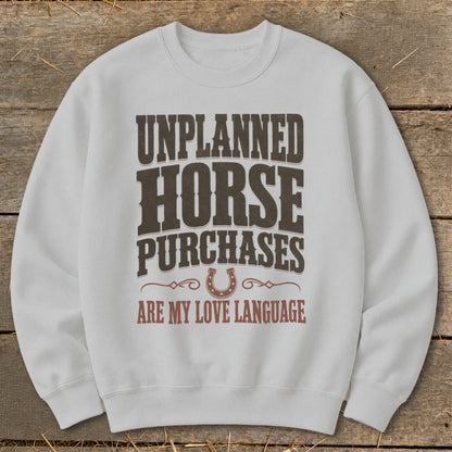 White sweatshirt with "Unplanned Horse Purchases Are My Love Language" text and horseshoe graphic.