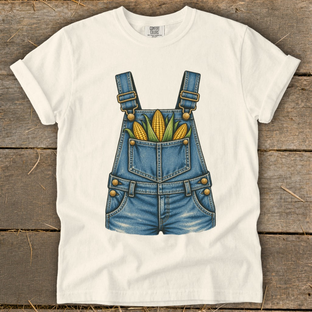 White t-shirt with a denim overalls graphic featuring three ears of corn.
