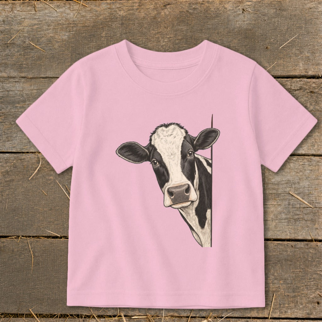Pink t-shirt with a black and white cow peeking from the side.