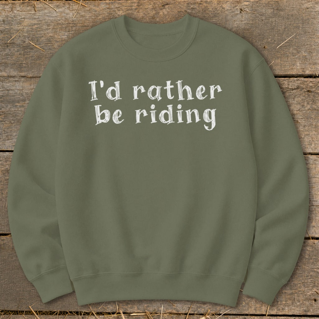 Olive green sweatshirt with white text "I'd rather be riding" on a wooden background.