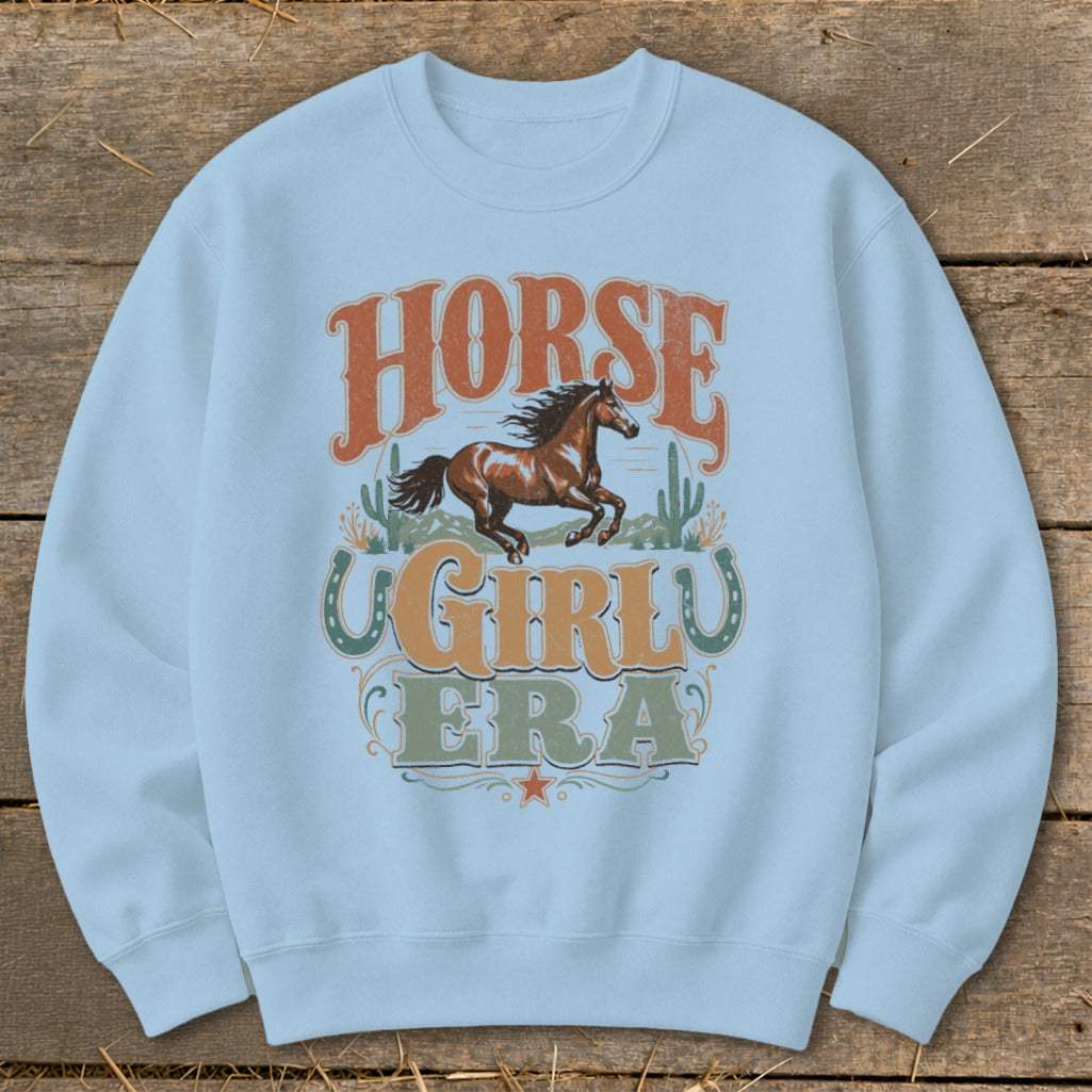 Light blue sweatshirt with "Horse Girl Era" graphic featuring a running horse and cacti.