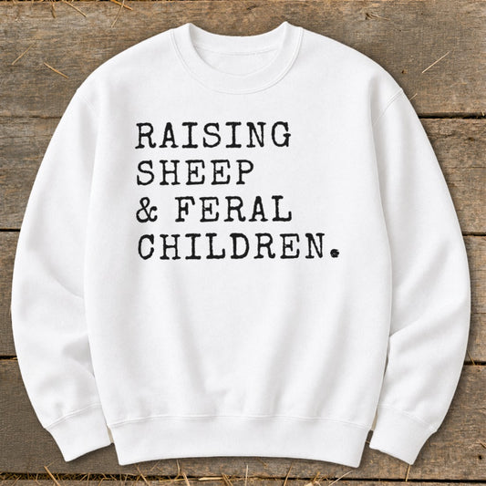 White sweatshirt with black text: "RAISING SHEEP & FERAL CHILDREN."
