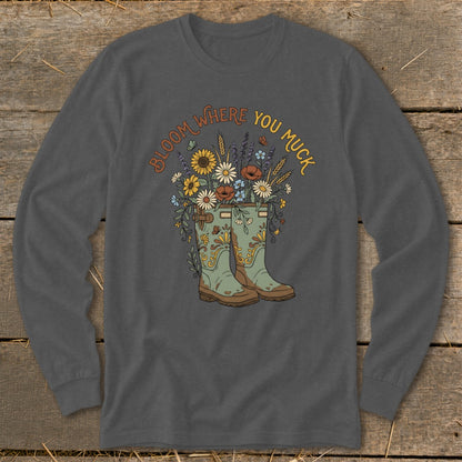 Long sleeve shirt with illustration of rain boots overflowing with flowers and text "Bloom Where You Muck."