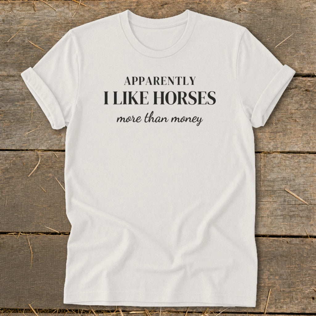 White t-shirt with black text: "APPARENTLY I LIKE HORSES more than money".