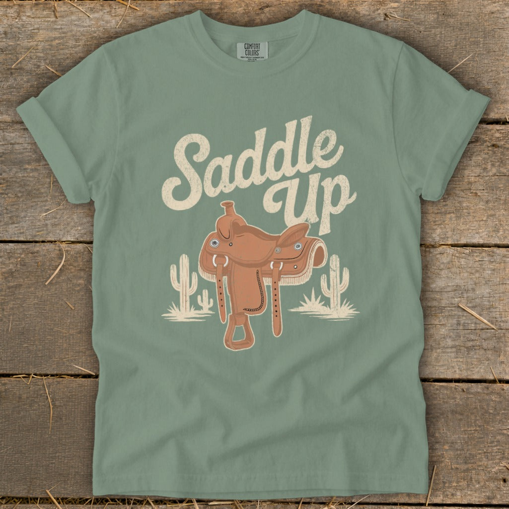 Green t-shirt with "Saddle Up" text and cowboy saddle illustration.