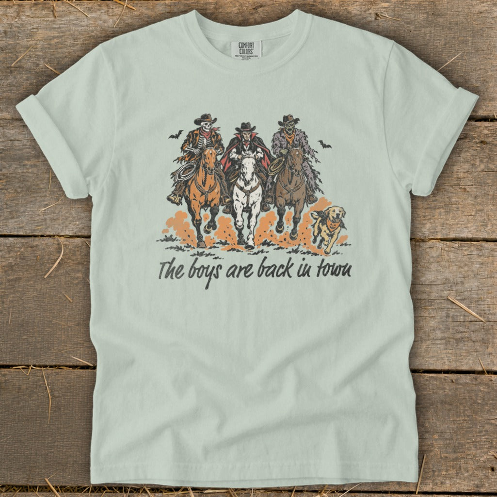 Skeleton, vampire, and zombie cowboys ride horses with a dog, text "The boys are back in town".