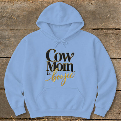 Light blue hoodie with "Cow Mom but boujee" text in black and gold.
