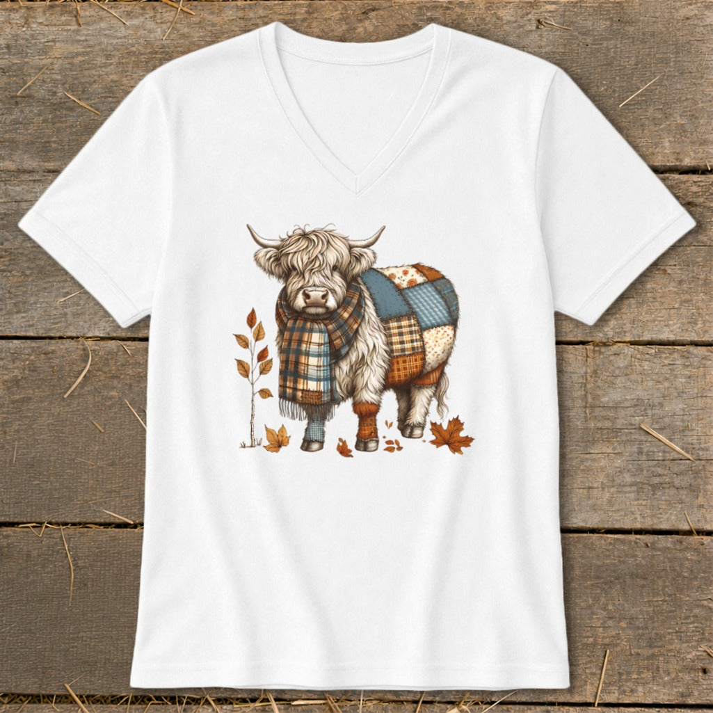 Highland cow in a plaid scarf and patchwork blanket, with autumn leaves.