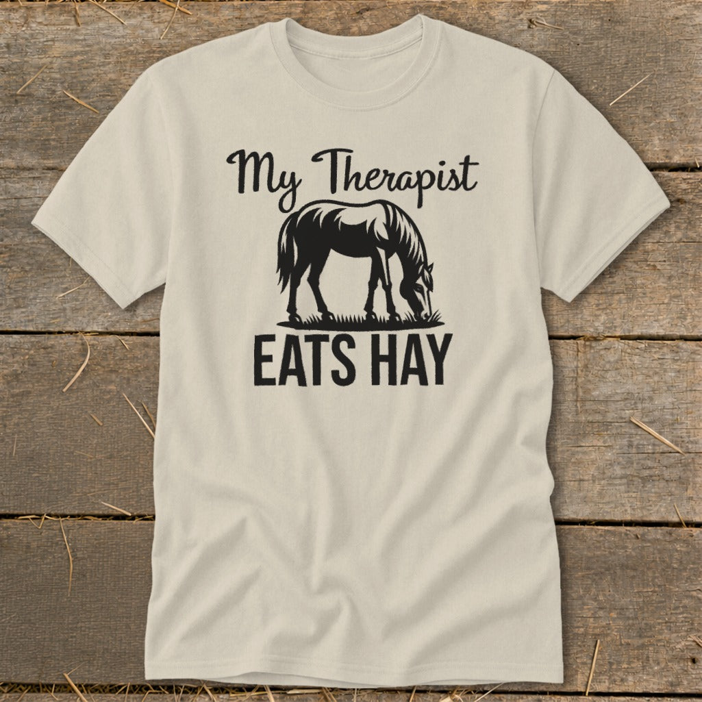 Cream t-shirt with graphic of a horse eating hay and text "My Therapist Eats Hay".