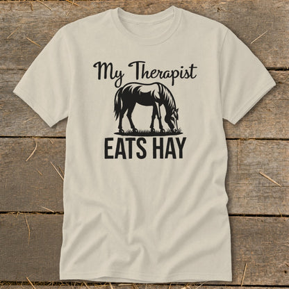 Cream t-shirt with graphic of a horse eating hay and text "My Therapist Eats Hay".