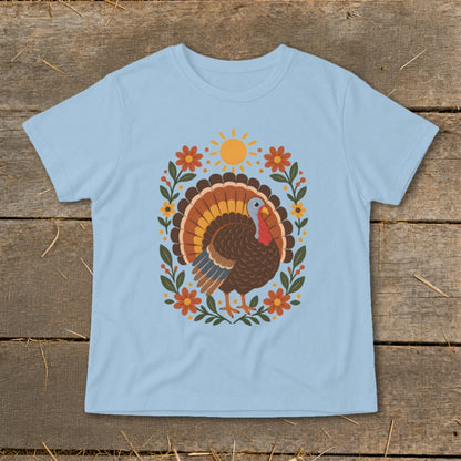 Light blue t-shirt with a cartoon turkey surrounded by flowers and a sun.