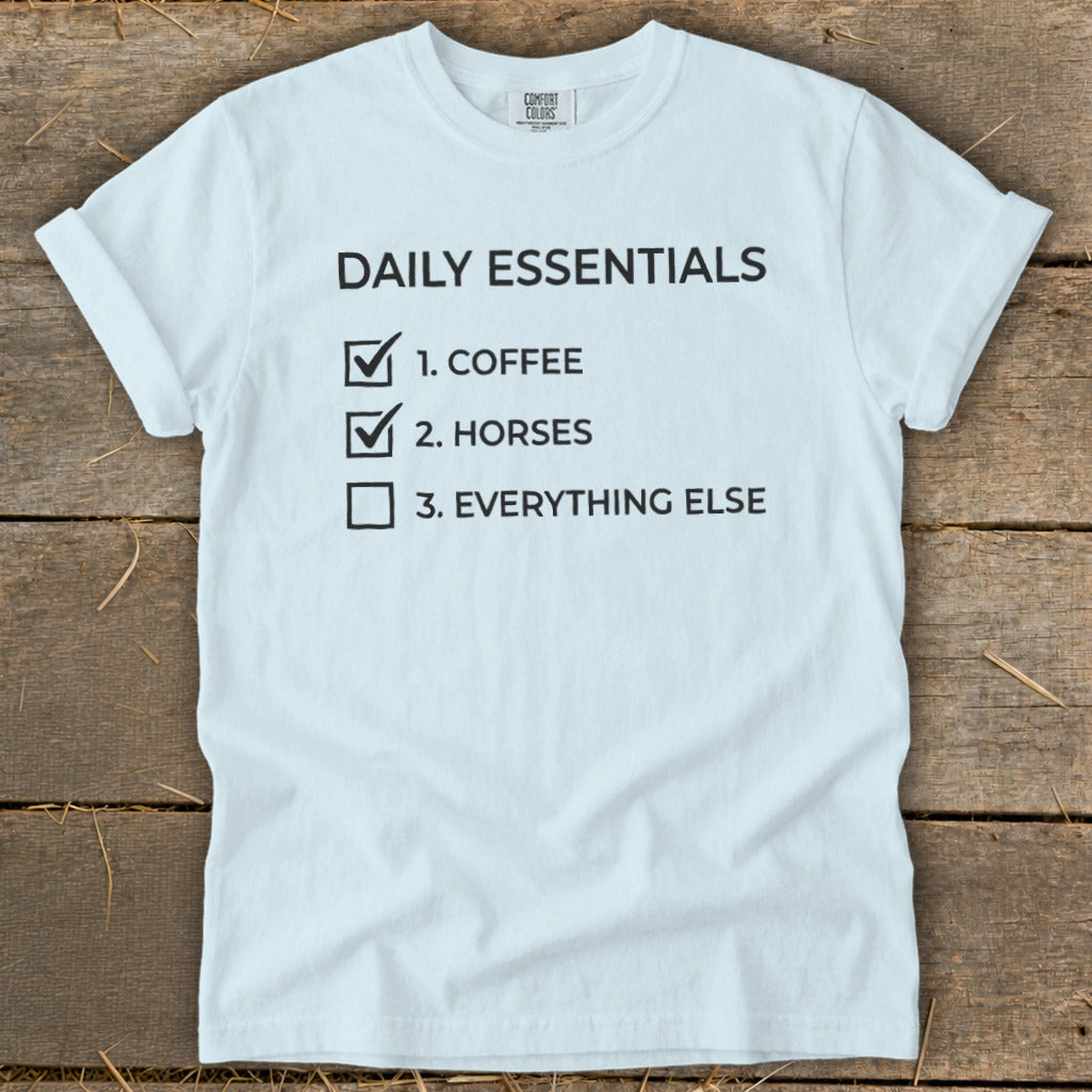 Light blue t-shirt with "Daily Essentials" checklist: coffee, horses, everything else.