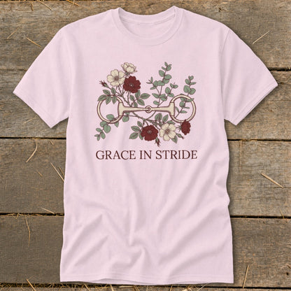 Pink t-shirt with horse bit and floral design, reads "GRACE IN STRIDE."