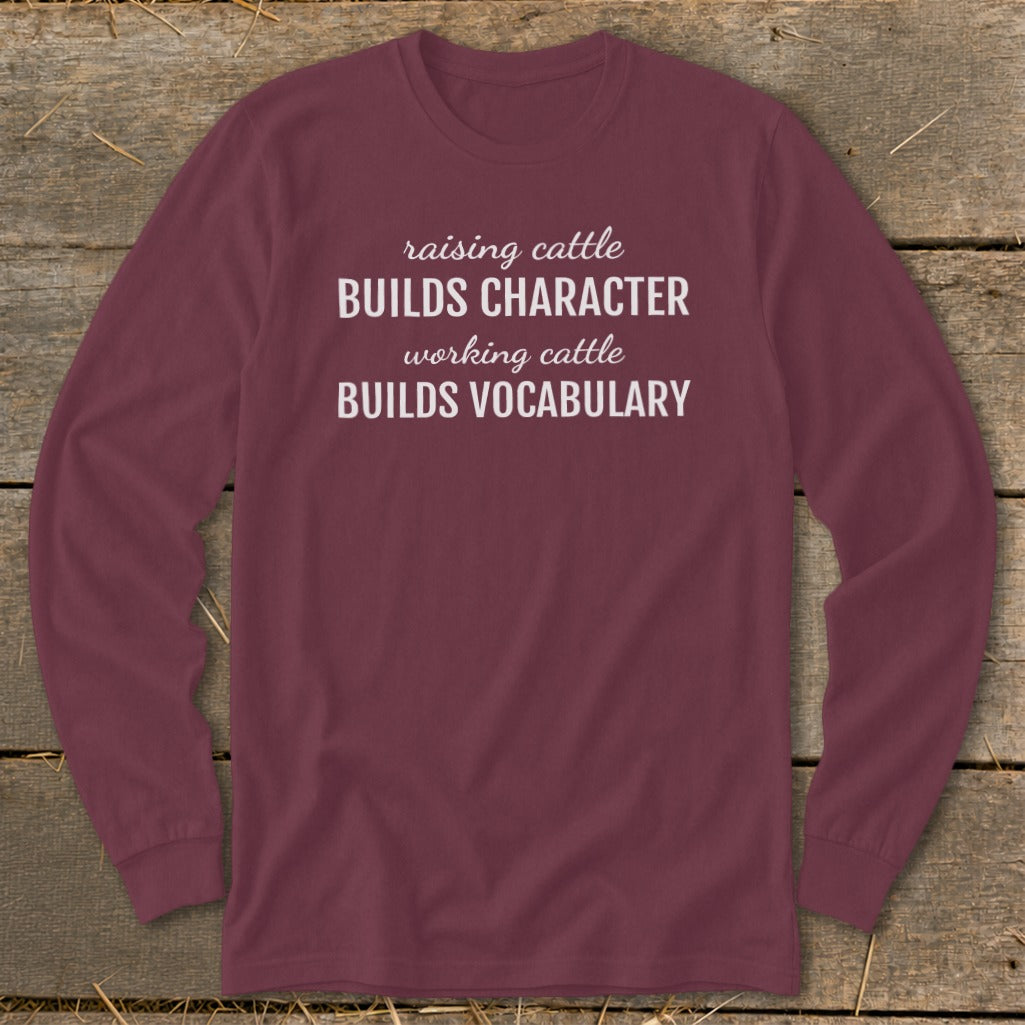 Maroon long-sleeve shirt with text "raising cattle BUILDS CHARACTER working cattle BUILDS VOCABULARY".