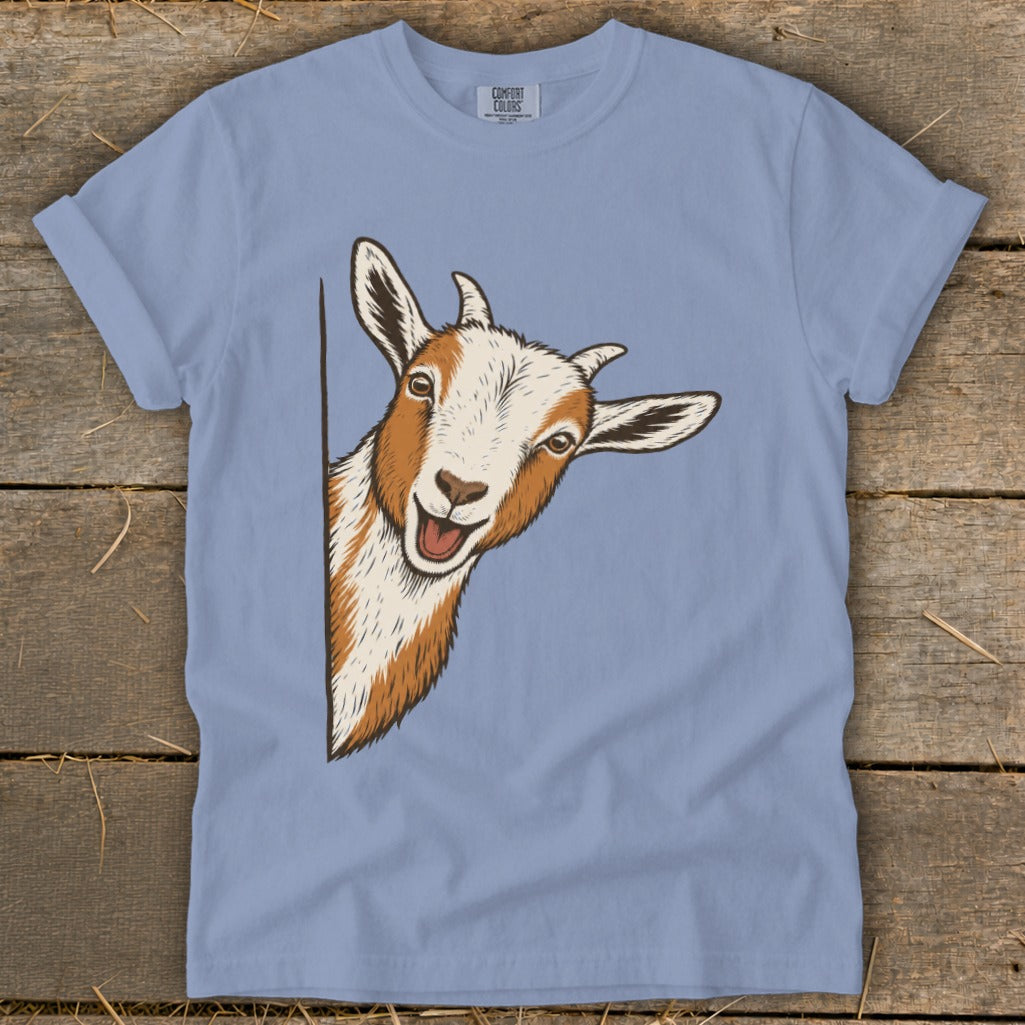 Illustration of a smiling goat peeking from the side on a light blue t-shirt.