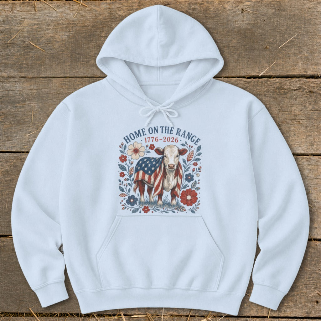 White hoodie with a cow wearing an American flag and floral design, text "HOME ON THE RANGE 1776-2026".
