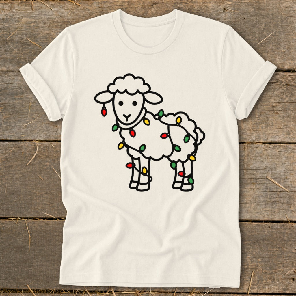 White t-shirt featuring a line drawing of a sheep tangled in colorful Christmas lights.