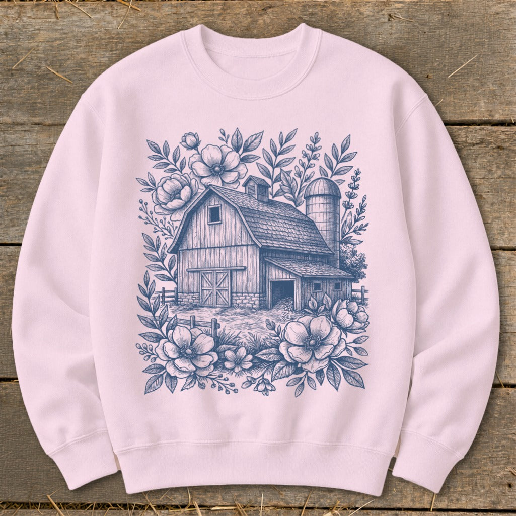 Pink sweatshirt with a blue line drawing of a barn and silo surrounded by flowers.