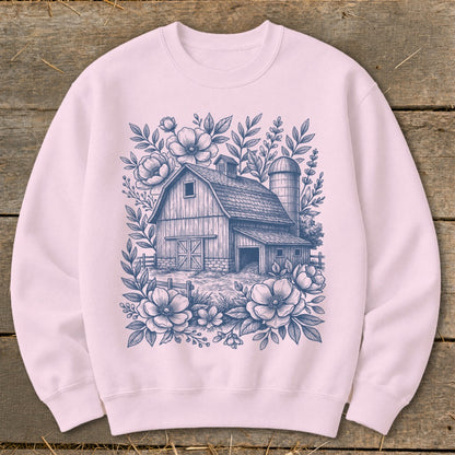 Pink sweatshirt with a blue line drawing of a barn and silo surrounded by flowers.