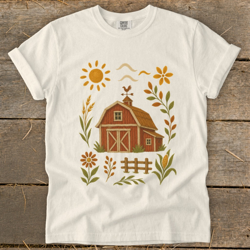 White t-shirt with a rustic barn, sun, and floral farm-themed graphic.