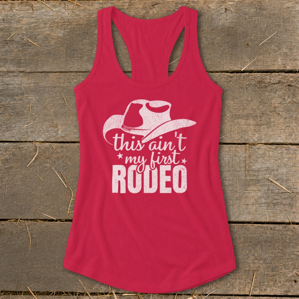Pink tank top with white cowboy hat graphic and "this ain't my first RODEO" text.