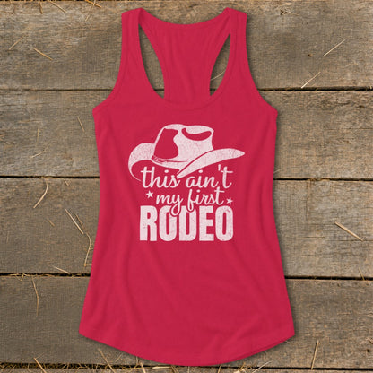 Pink tank top with white cowboy hat graphic and "this ain't my first RODEO" text.