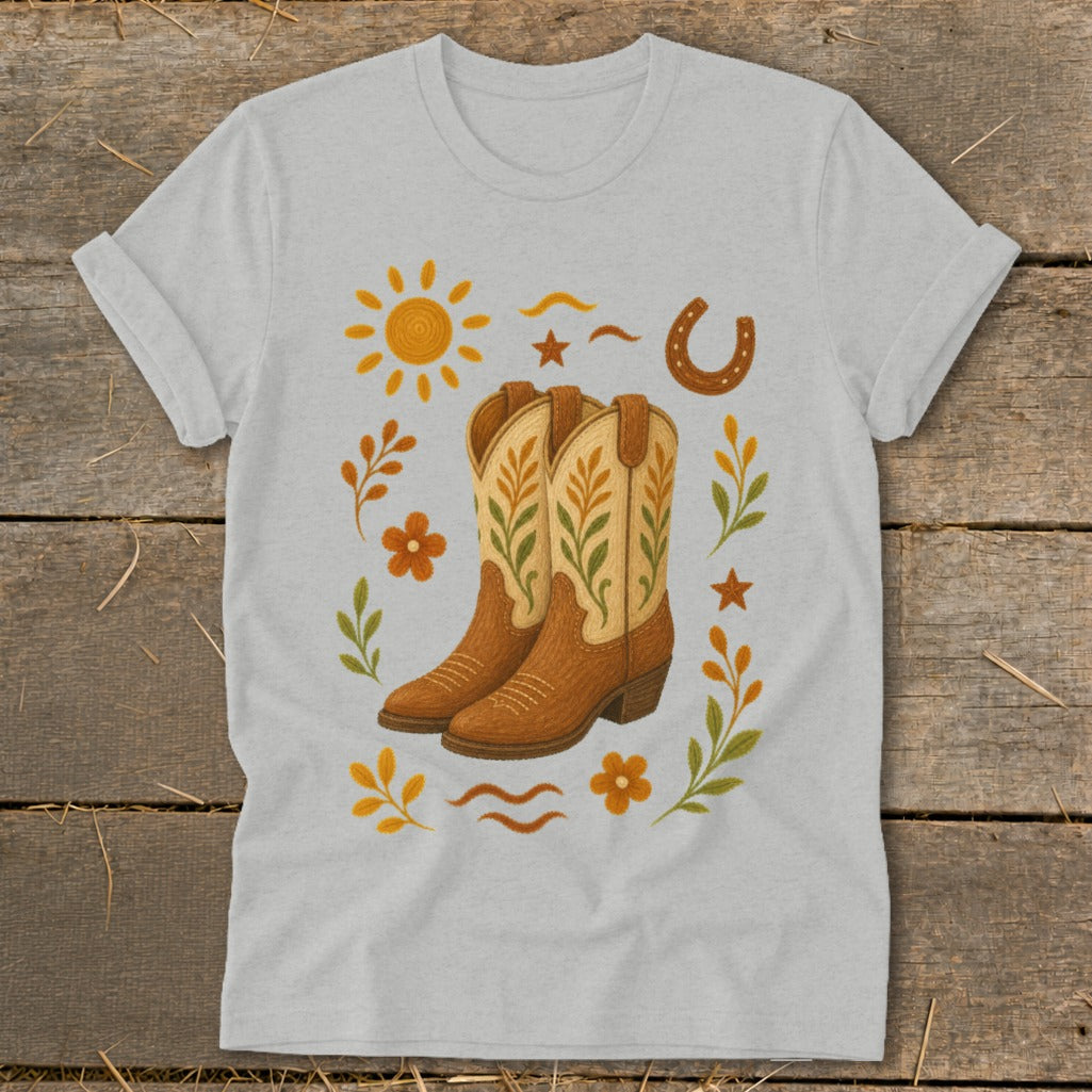 Light gray t-shirt with a design of brown cowboy boots surrounded by western-themed graphics.