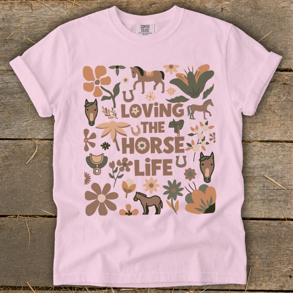 Pink t-shirt with "Loving The Horse Life" graphic featuring horses, flowers, and saddles.