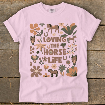 Pink t-shirt with "Loving The Horse Life" graphic featuring horses, flowers, and saddles.