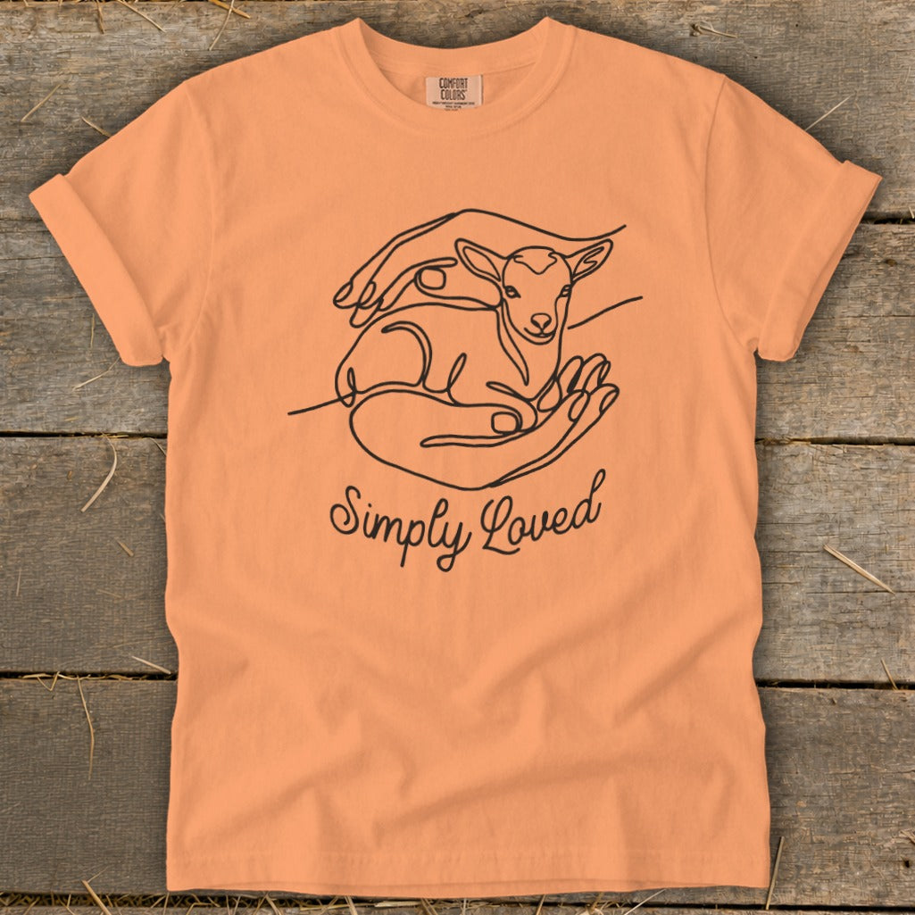 Peach t-shirt with line art of a lamb in hands and "Simply Loved" text.