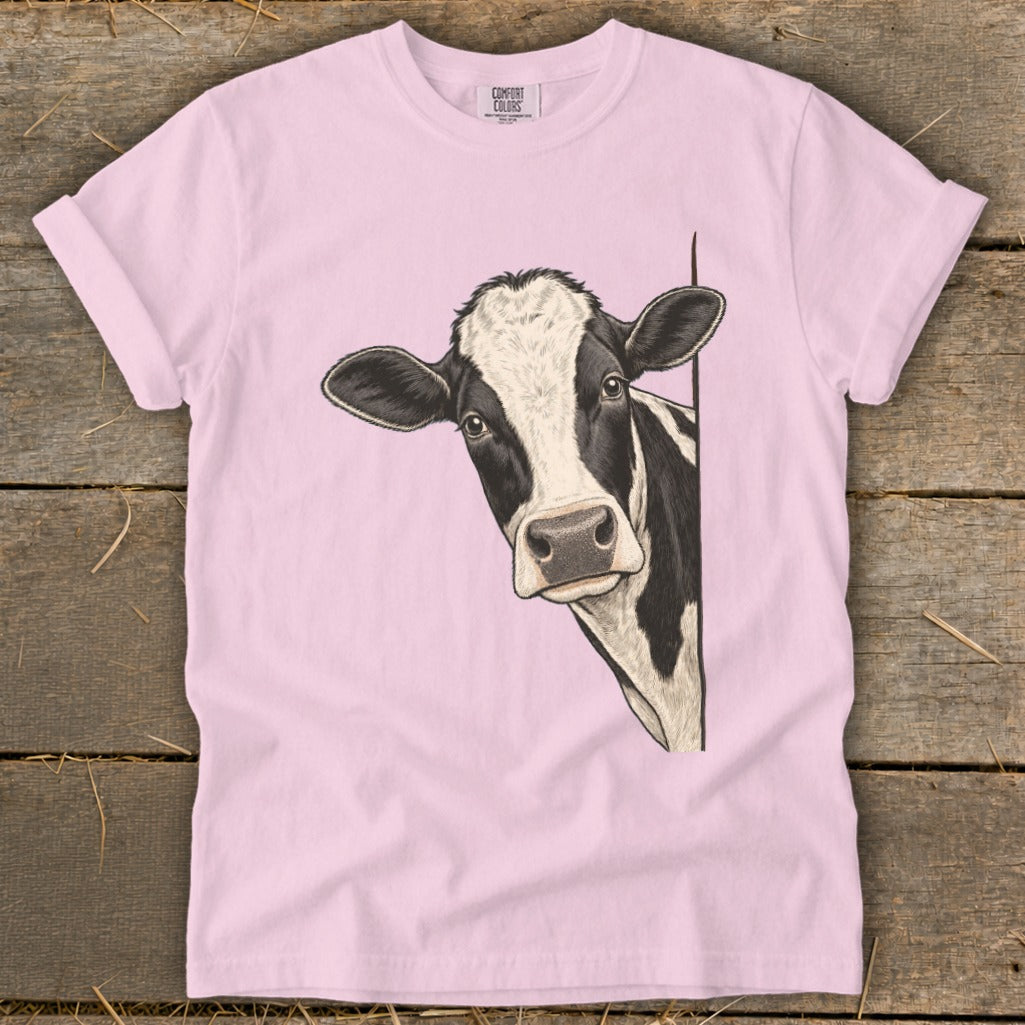 Pink t-shirt with a black and white cow peeking around the side.