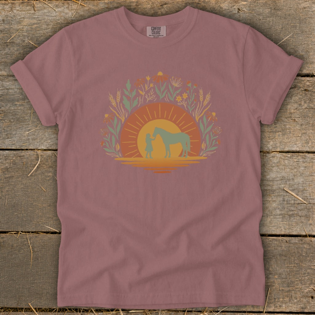 T-shirt with a graphic of a child and horse at sunset surrounded by flowers.