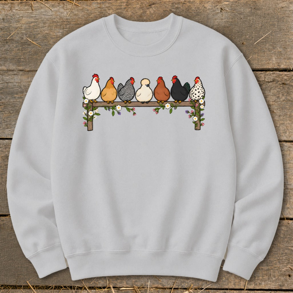 Light gray crewneck sweatshirt featuring a graphic of seven cartoon chickens perched on a flower-covered wooden fence.