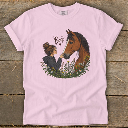 Illustration of a girl booping a horse's nose surrounded by flowers.