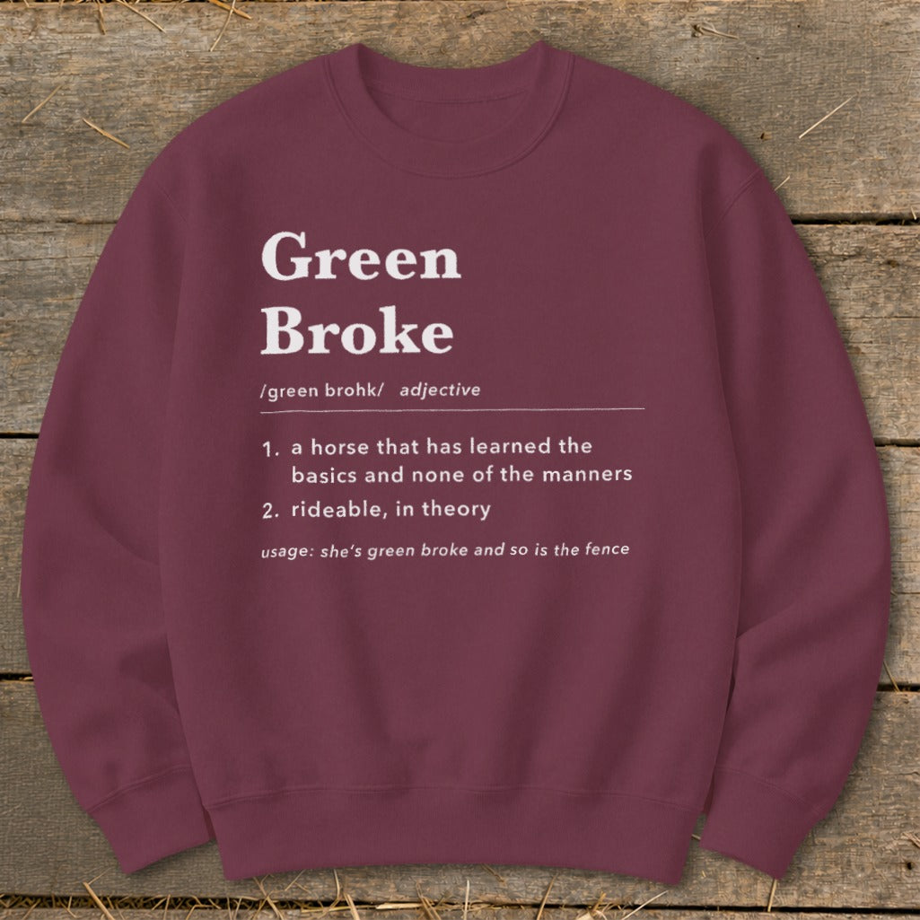 Maroon crewneck sweatshirt featuring white dictionary-style text defining Green Broke laid on rustic wood.