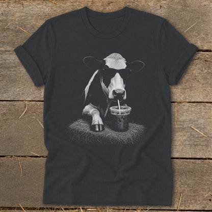 Cow wearing sunglasses drinks from a cup with a straw on a bale of hay.