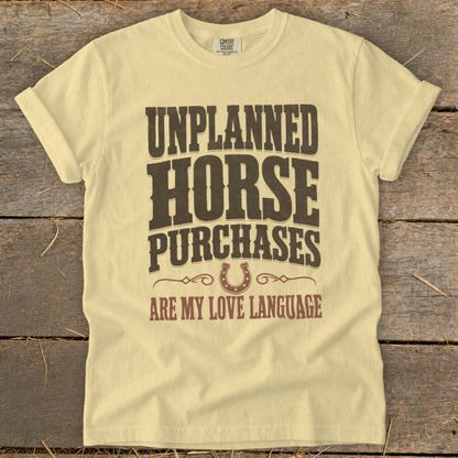 Light yellow t-shirt with "Unplanned Horse Purchases Are My Love Language" text and horseshoe graphic.