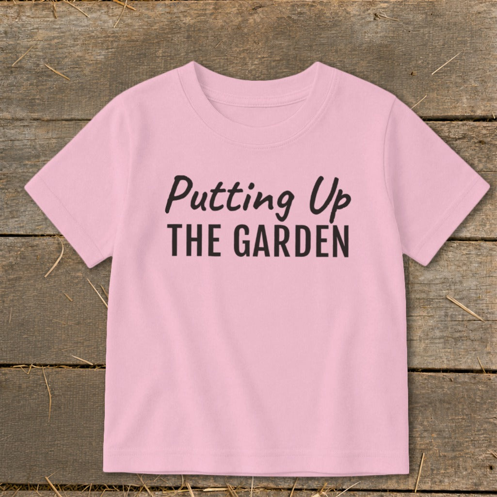 Pink t-shirt with black text "Putting Up THE GARDEN"