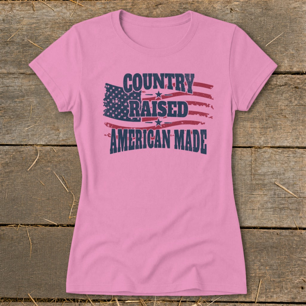 Pink t-shirt with distressed American flag graphic and text "COUNTRY RAISED AMERICAN MADE".