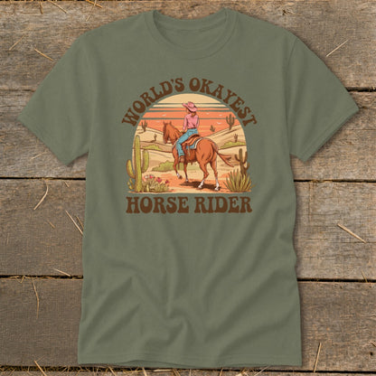 T-shirt graphic with cowboy riding horse in desert landscape, text "World's Okayest Horse Rider".