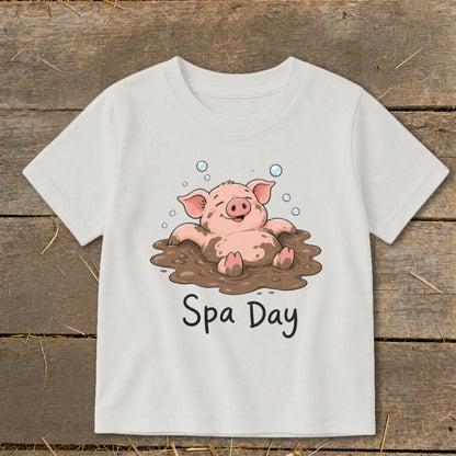 White t-shirt with cartoon pig relaxing in mud, text "Spa Day"