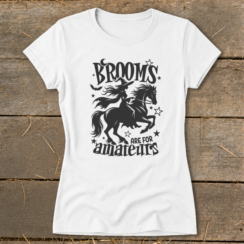 White t-shirt with black graphic of a witch riding a horse, text "Brooms are for amateurs".