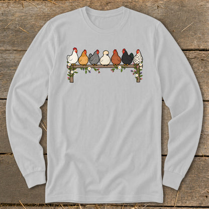 Light gray long-sleeve t-shirt featuring an illustration of seven colorful chickens perched on a flower-decorated wooden fence.