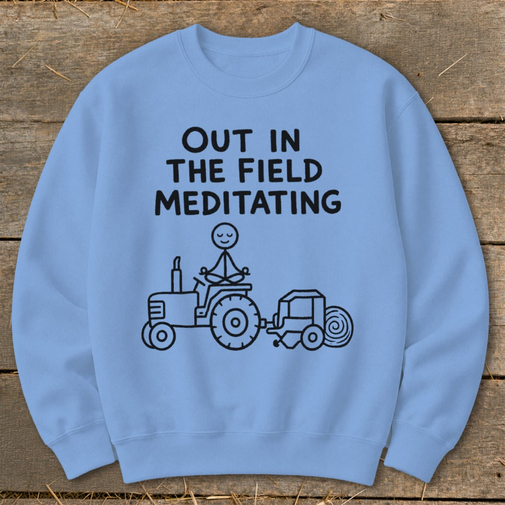 Light blue sweatshirt with black text and drawing of meditating figure on tractor.