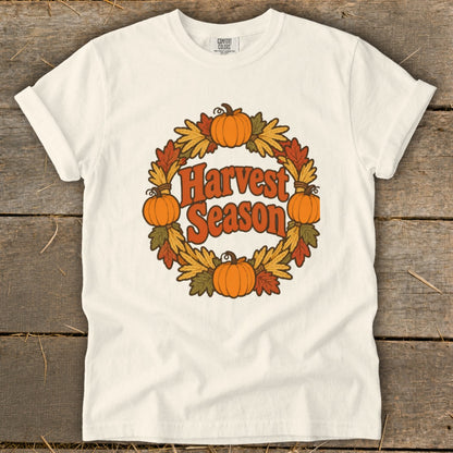Cream t-shirt with "Harvest Season" text in a pumpkin and leaf wreath graphic.
