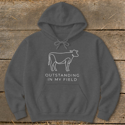 Dark grey hoodie with white line drawing of a cow and text "OUTSTANDING IN MY FIELD".